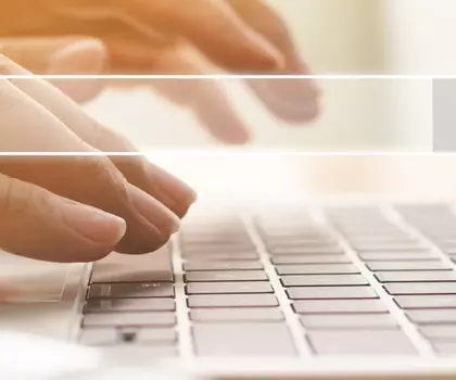 Hände tippen auf einer Laptop-Tastatur mit eingeblendeter Suchleiste.