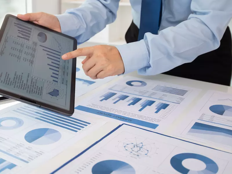 Geschäftsmann in blauem Anzug, der auf Diagramme an seinem Tablet zeigt