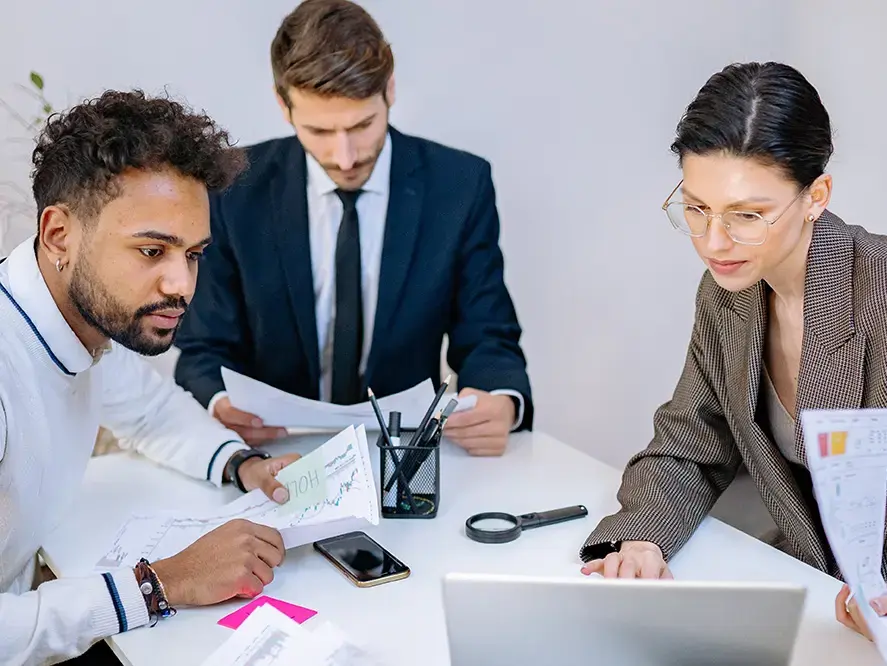 Drei Geschäftsleute haben ein Meeting und schauen Unterlagen durch