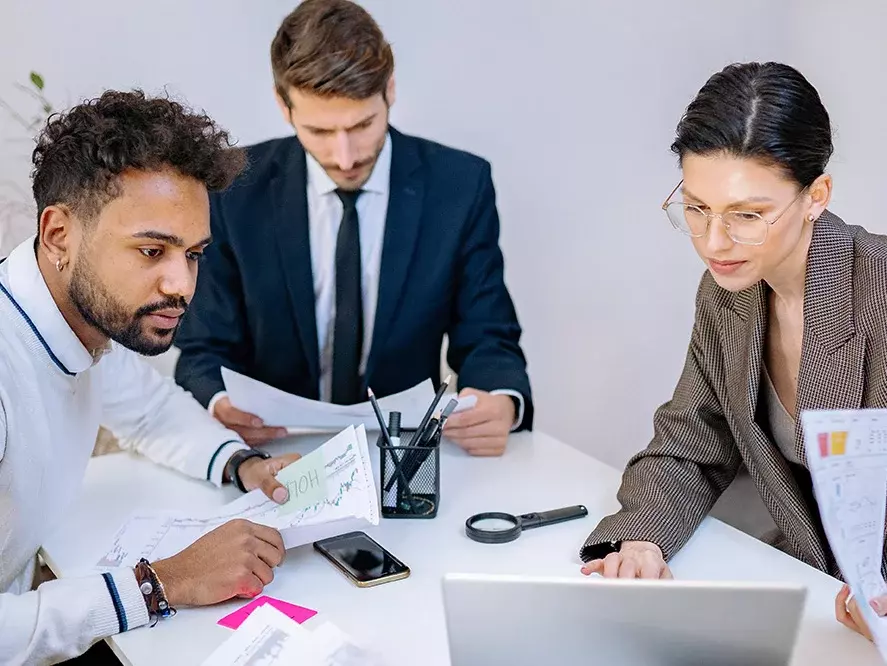 Drei Geschäftsleute haben ein Meeting und schauen Unterlagen durch