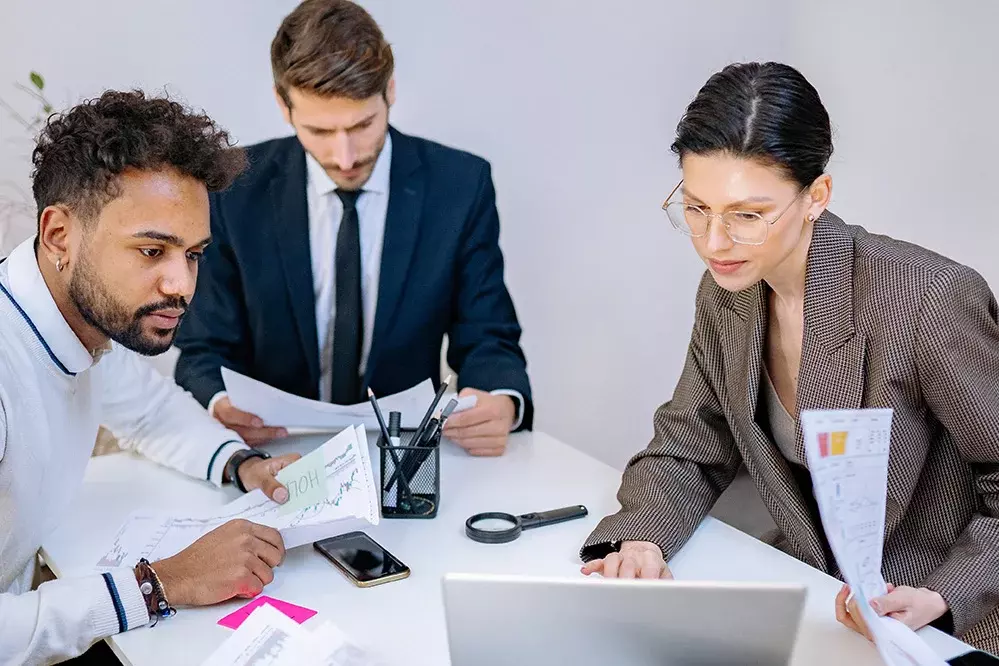 Bild von 3 Kollegen bei der Arbeit am Laptop