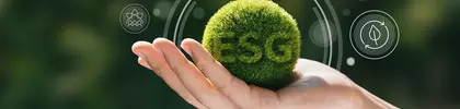 Hand hält eine grüne Kugel mit der Aufschrift ‚ESG‘, im Hintergrund digitale Symbole – Symbolbild für Umwelt, Soziales und Unternehmensführung.