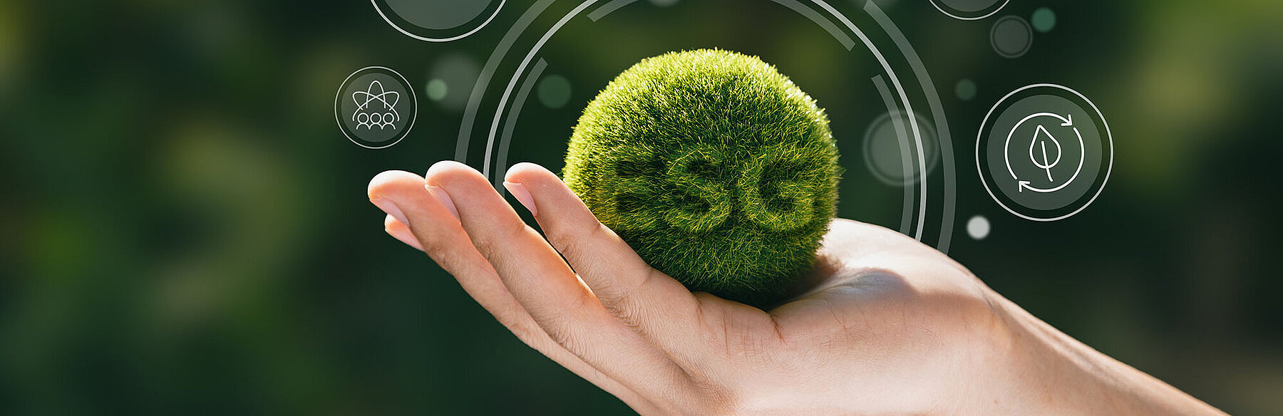 Hand hält eine grüne Kugel mit der Aufschrift ‚ESG‘, im Hintergrund digitale Symbole – Symbolbild für Umwelt, Soziales und Unternehmensführung.