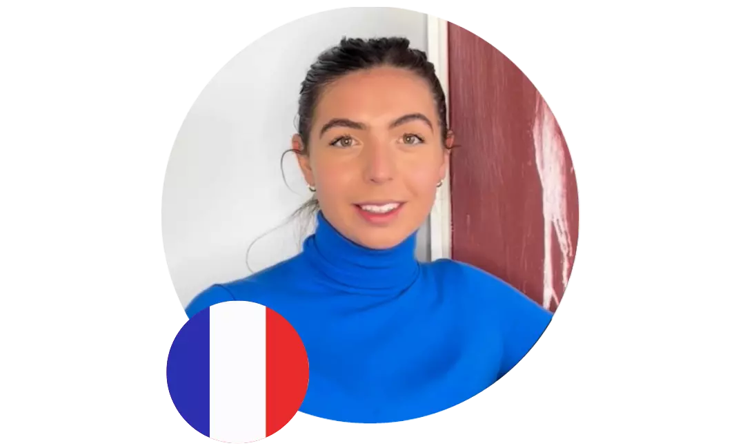 Junge Frau in blauem Oberteil vor hellem Hintergrund, unten links im Bild ist eine französische Flagge eingeblendet.