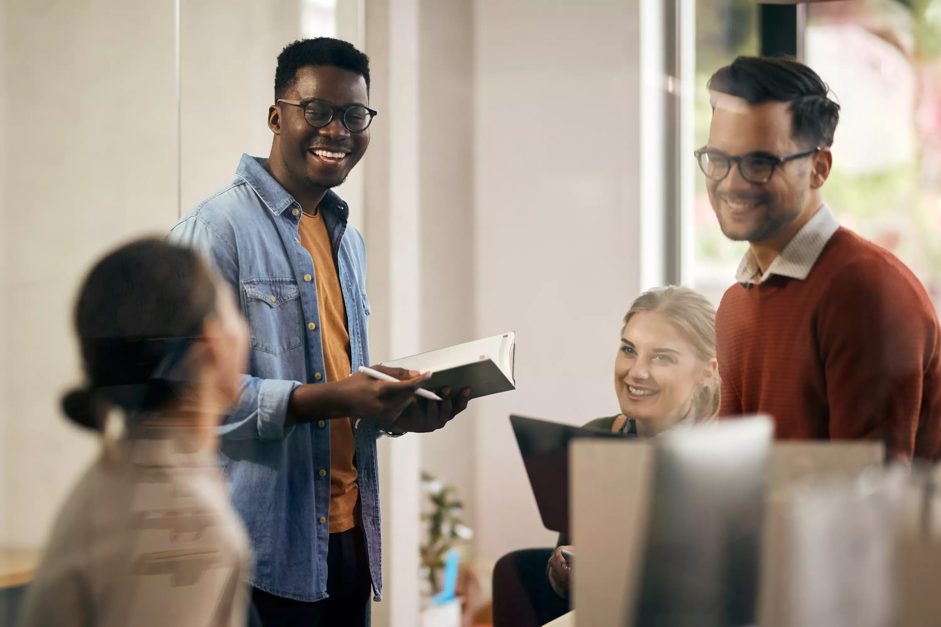 3 junge Menschen unterhalten sich und arbeiten gemeinsam an einem Projekt – Symbolbild für Teamarbeit und kreative Zusammenarbeit.