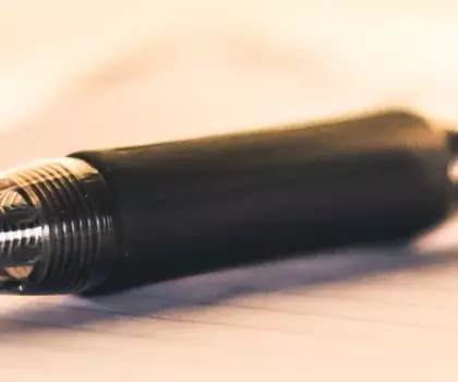 Nahaufnahme eines schwarzen Kugelschreibers, der auf einem weißen Notizblock liegt – Symbol für Schreiben, Planung oder Büroarbeit.