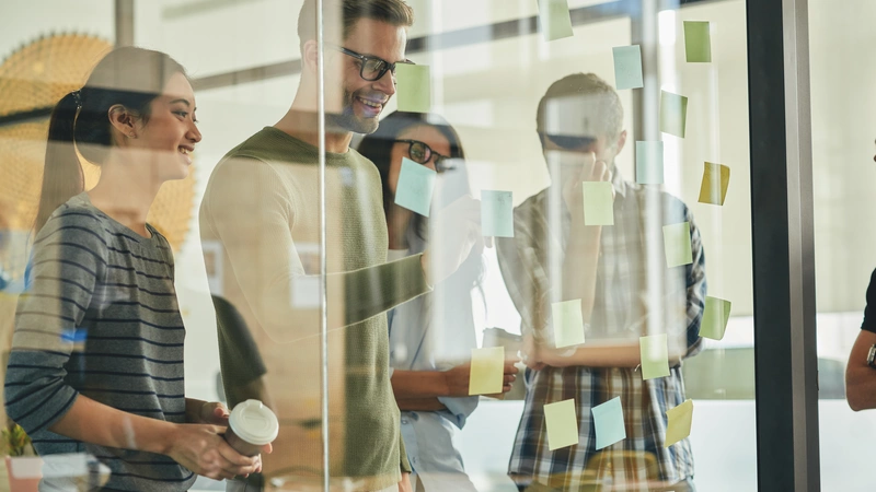Bild von Teamkollegen, die mit Post-It Notizen Brainstorming betreiben