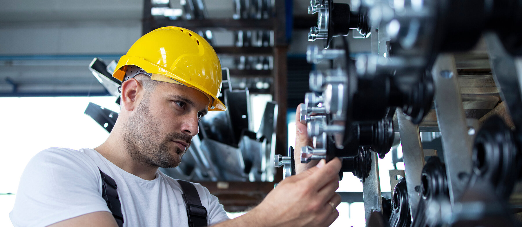 Handwerker mit gelbem Schutzhelm arbeitet an einer Rohr- und Ventiltechnik – Symbolbild für Industrie, Wartung oder Anlagenmechanik.