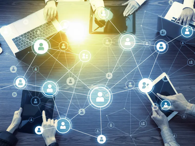 Personen, die in einem Kreis an Laptops zusammensitzen und vernetzt arbeiten