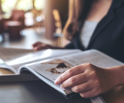 Bild einer Person, die ein Magazin aufgeschlagen hält