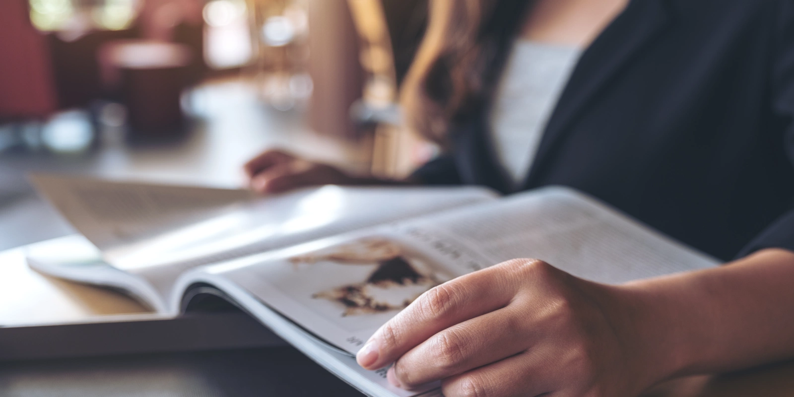 Bild einer Person, die ein Magazin aufgeschlagen hält