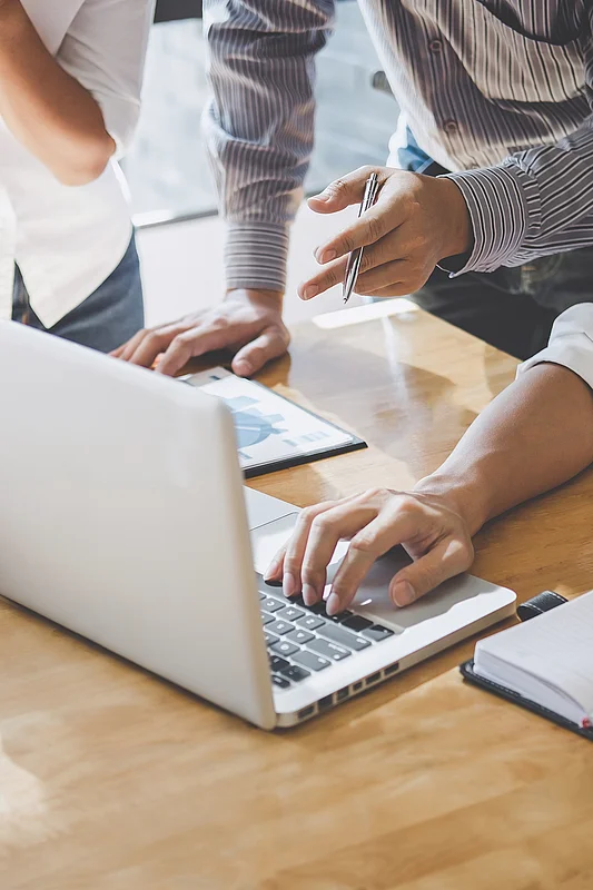 Bild dreier Arbeitskollegen, die an einem Laptop gemeinsam arbeiten