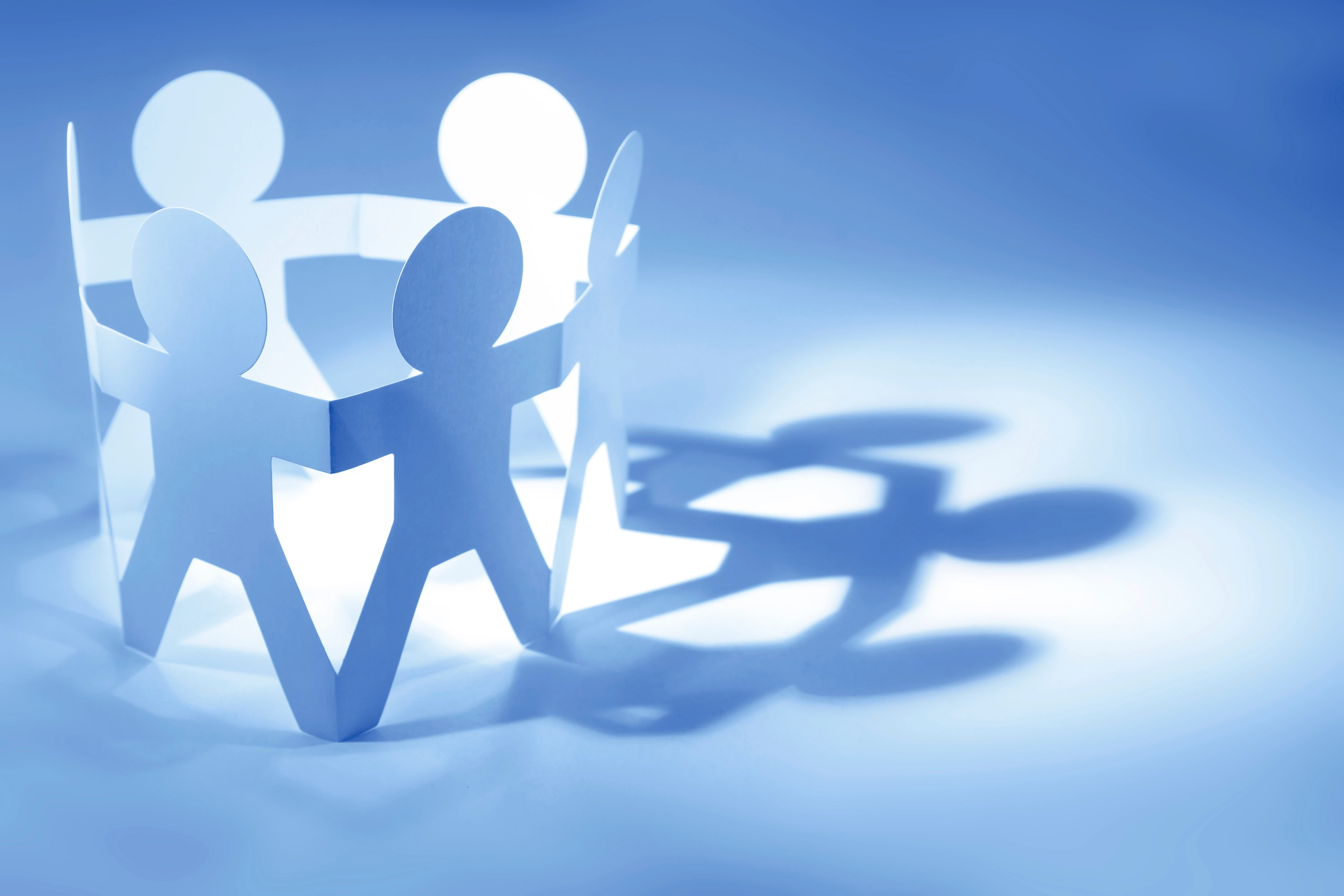 Papierfiguren in Kreisform werfen einen Schatten in Form eines Eurozeichens – Symbolbild für Gemeinschaft und Finanzen.