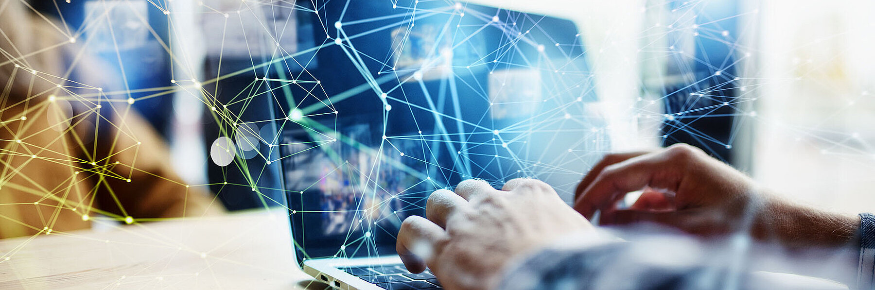 Person tippt auf einem Laptop, überlagert von digitalen Netzwerklinien und Datenpunkten – Symbolbild für Digitalisierung und Vernetzung.