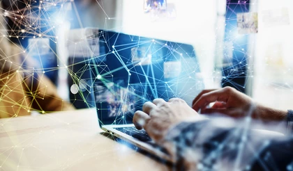 Bild einer Geschäftsperson, die an einem Laptop arbeitet, über ihr sind digitale Icons eingezeichnet, die Vernetzung symbolisieren