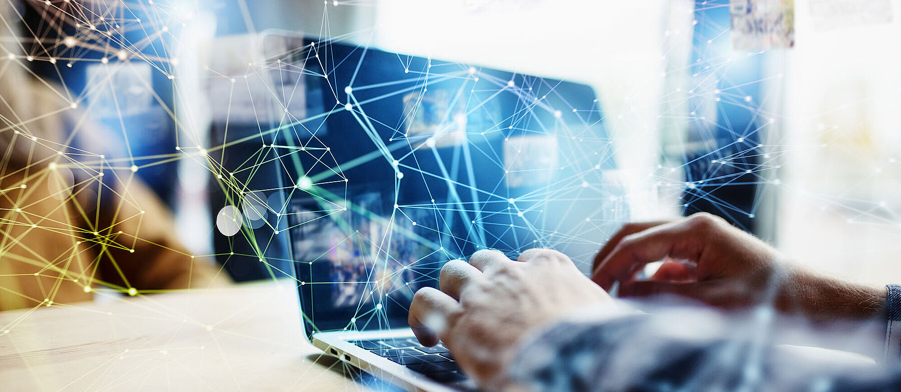 Person tippt auf einem Laptop, überlagert von digitalen Netzwerklinien und Datenpunkten – Symbolbild für Digitalisierung und Vernetzung.