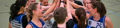 Basketballteam steht im Kreis und streckt motiviert die Hände zur Mitte als Zeichen des Teamgeists.