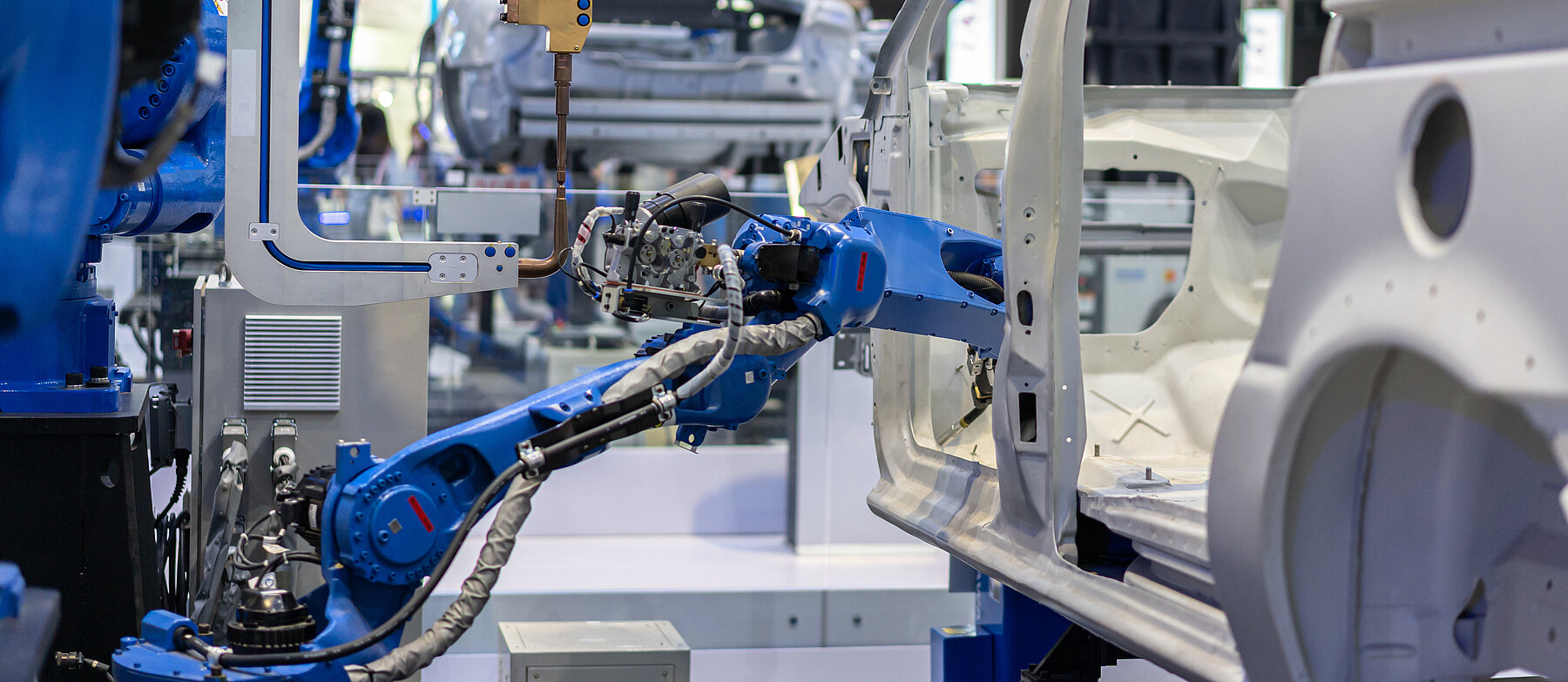 Industrieroboter mit Greifarmen arbeiten in einer automatisierten Produktionslinie – Symbol für Industrie 4.0 und moderne Fertigungstechnik.