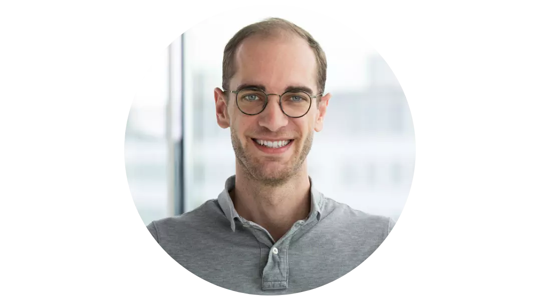 Geschäftsmann mit Brille schaut lächelnd in die Kamera.